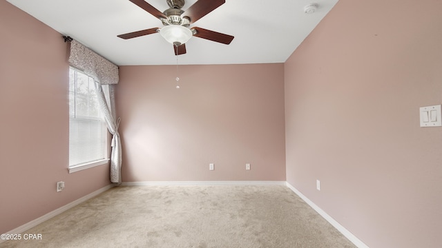 carpeted spare room featuring a ceiling fan and baseboards