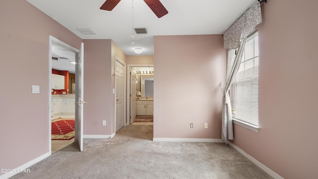 unfurnished bedroom with multiple windows, visible vents, ensuite bathroom, and carpet floors