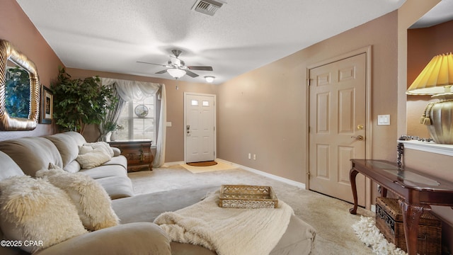 living area featuring visible vents, baseboards, light colored carpet, a textured ceiling, and a ceiling fan