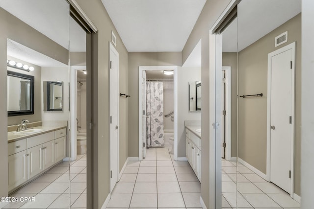 bathroom with baseboards, toilet, vanity, and tile patterned flooring