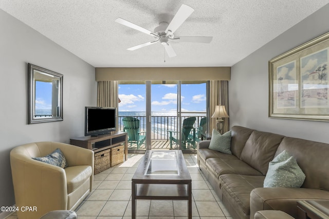 living area with light tile patterned floors, a ceiling fan, and a textured ceiling