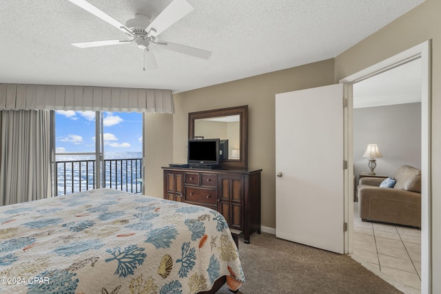 carpeted bedroom featuring a textured ceiling, ceiling fan, tile patterned flooring, and access to outside