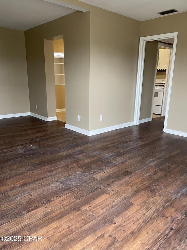 empty room with dark wood-style floors, baseboards, and visible vents