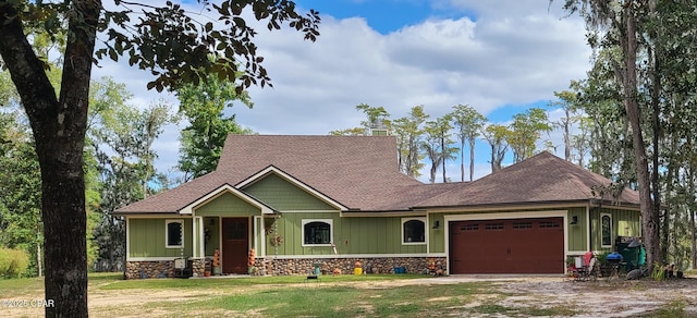 view of front of house featuring an attached garage, stone siding, a front lawn, and board and batten siding