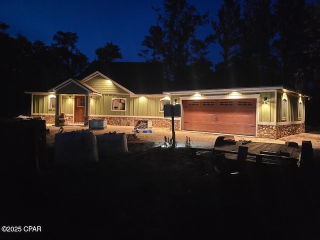 view of front facade featuring a garage, stone siding, and board and batten siding