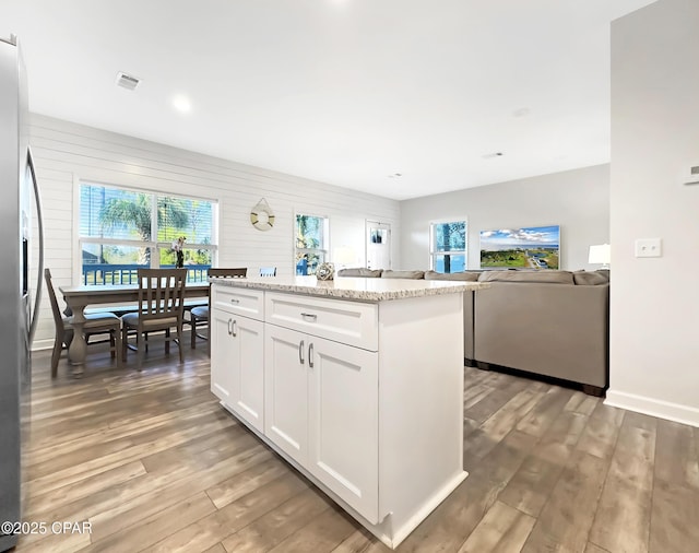 kitchen with light wood-type flooring, white cabinets, a healthy amount of sunlight, and stainless steel fridge with ice dispenser