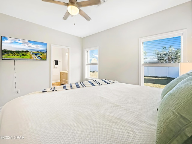 bedroom with ensuite bathroom, multiple windows, and a ceiling fan