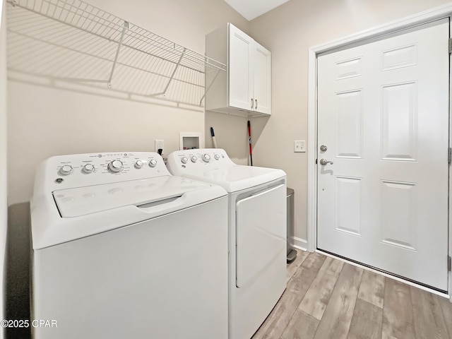 washroom with light wood-style flooring, washing machine and clothes dryer, and cabinet space