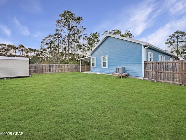 view of yard with an outbuilding, a fenced backyard, and central AC