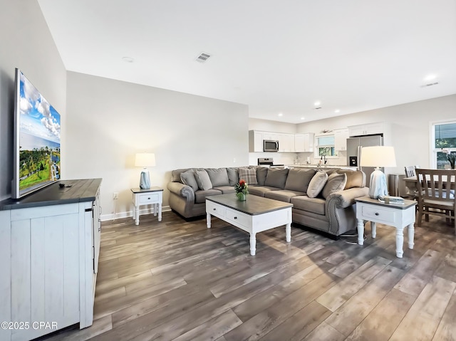 living room featuring baseboards, visible vents, wood finished floors, and recessed lighting