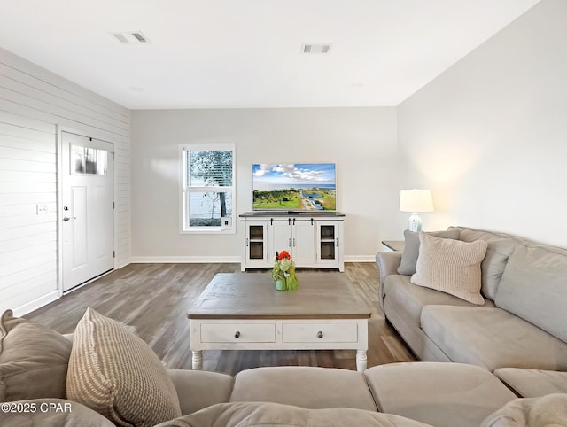 living area with wood finished floors, visible vents, and baseboards