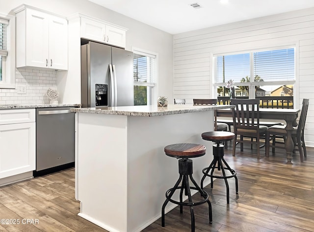 kitchen with stainless steel appliances, tasteful backsplash, a breakfast bar area, and wood finished floors