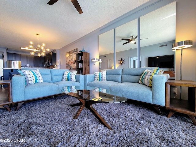 living area featuring carpet, visible vents, a textured ceiling, and ceiling fan with notable chandelier