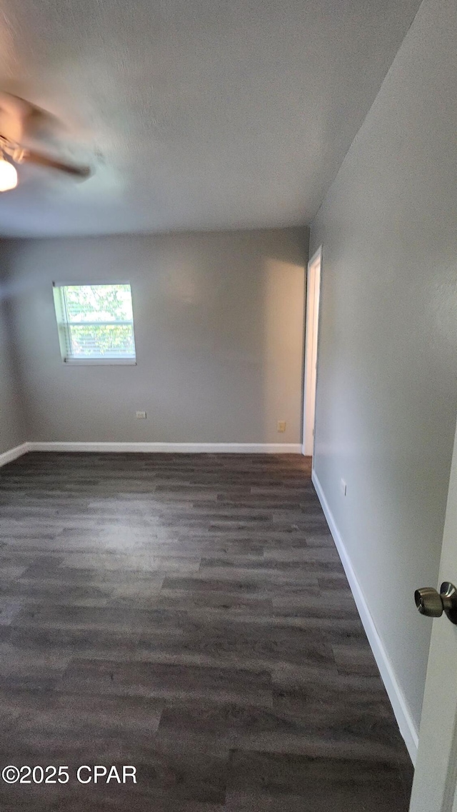 empty room with dark wood-type flooring, baseboards, and a textured ceiling