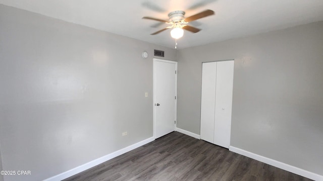 unfurnished bedroom featuring a closet, baseboards, dark wood-type flooring, and visible vents