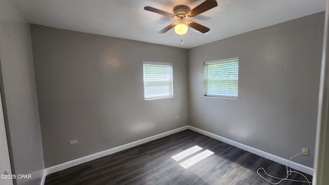 empty room with dark wood finished floors, a ceiling fan, and baseboards