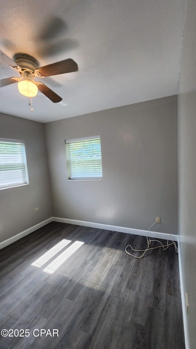 unfurnished room with a wealth of natural light, baseboards, and dark wood finished floors