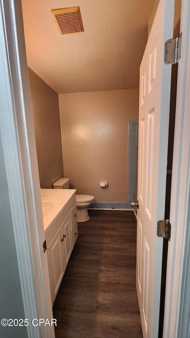 bathroom featuring visible vents, toilet, wood finished floors, baseboards, and vanity