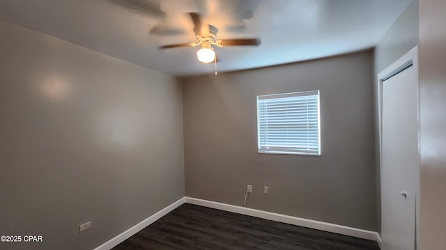 spare room featuring baseboards, dark wood-type flooring, and a ceiling fan