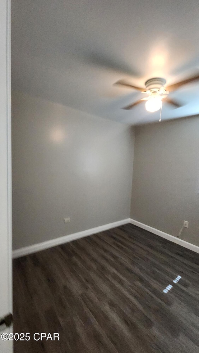 unfurnished room with dark wood finished floors, a ceiling fan, and baseboards