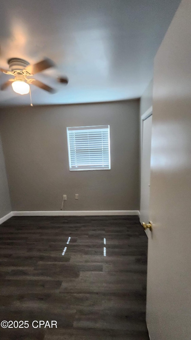 empty room with ceiling fan, baseboards, and dark wood-style flooring
