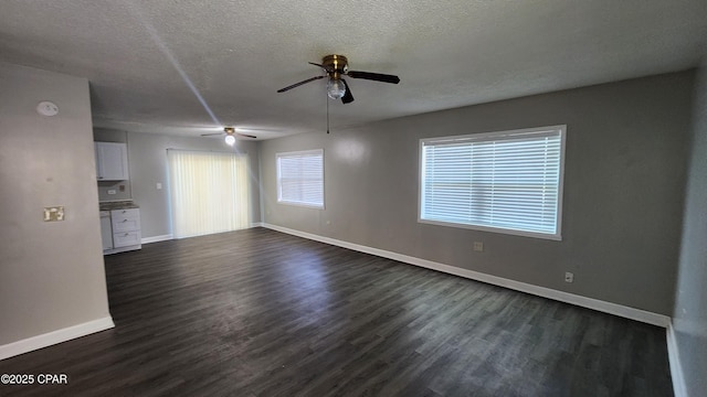 unfurnished living room featuring baseboards, a ceiling fan, dark wood-style flooring, and a textured ceiling