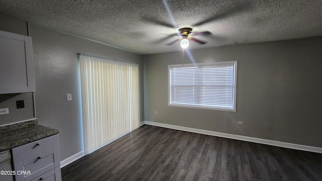 unfurnished dining area featuring dark wood-style floors, baseboards, and ceiling fan