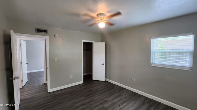 unfurnished bedroom featuring visible vents, baseboards, dark wood finished floors, a closet, and a ceiling fan