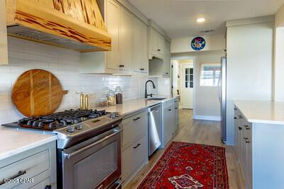 kitchen with under cabinet range hood, stainless steel appliances, a sink, light wood-style floors, and light countertops