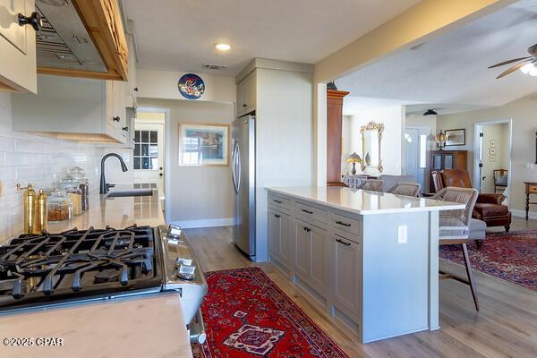 kitchen with freestanding refrigerator, open floor plan, a sink, ceiling fan, and a kitchen bar