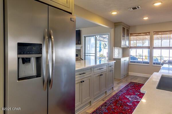 kitchen featuring light countertops, a wealth of natural light, stainless steel fridge, and visible vents