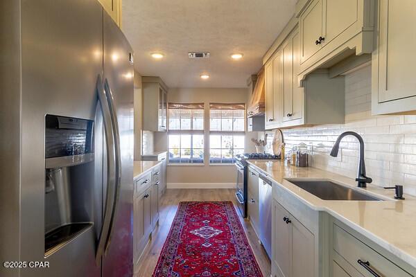 kitchen with appliances with stainless steel finishes, light countertops, a sink, and visible vents