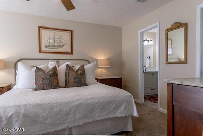 carpeted bedroom with ensuite bath, baseboards, and ceiling fan