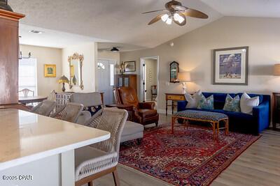 living area with lofted ceiling, ceiling fan, and wood finished floors