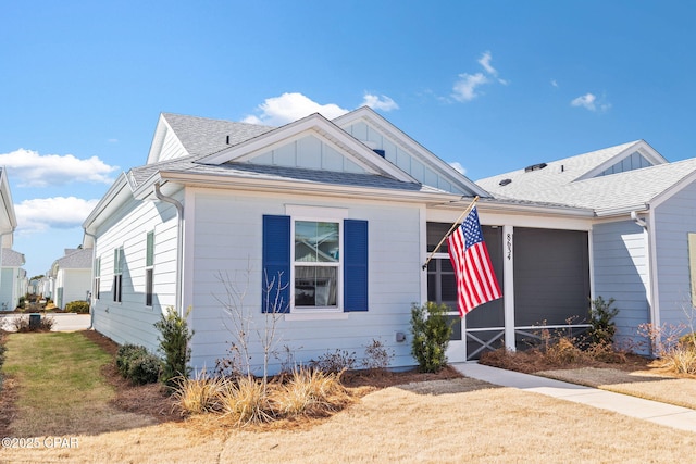 bungalow featuring roof with shingles, board and batten siding, and a front yard