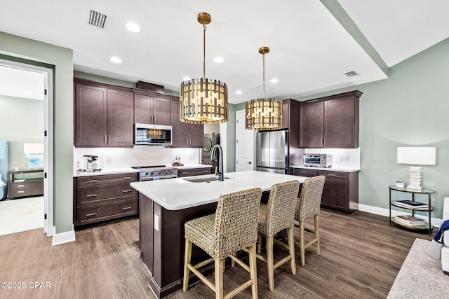 kitchen featuring visible vents, a sink, appliances with stainless steel finishes, and dark wood-type flooring