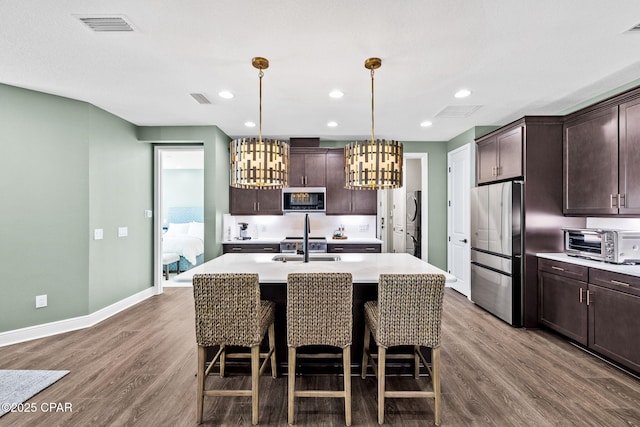 kitchen featuring visible vents, appliances with stainless steel finishes, a toaster, and dark brown cabinetry