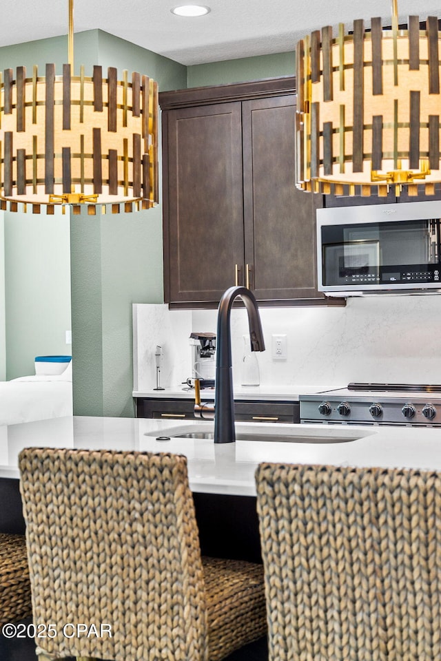 kitchen featuring a sink, stainless steel microwave, range, and dark brown cabinetry