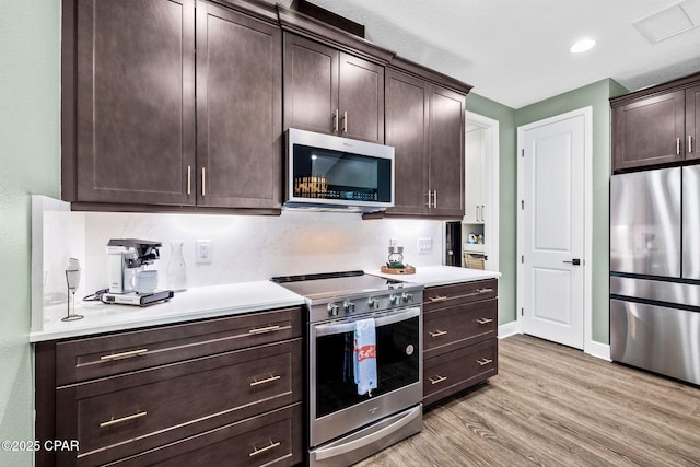 kitchen featuring light wood-style floors, light countertops, stainless steel appliances, and dark brown cabinets