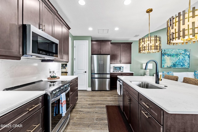 kitchen featuring dark brown cabinetry, dark wood-type flooring, light countertops, a sink, and stainless steel appliances