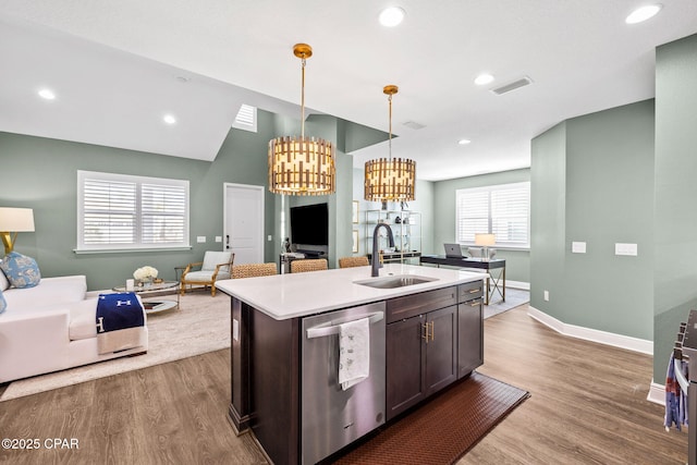 kitchen featuring stainless steel dishwasher, open floor plan, a sink, and wood finished floors
