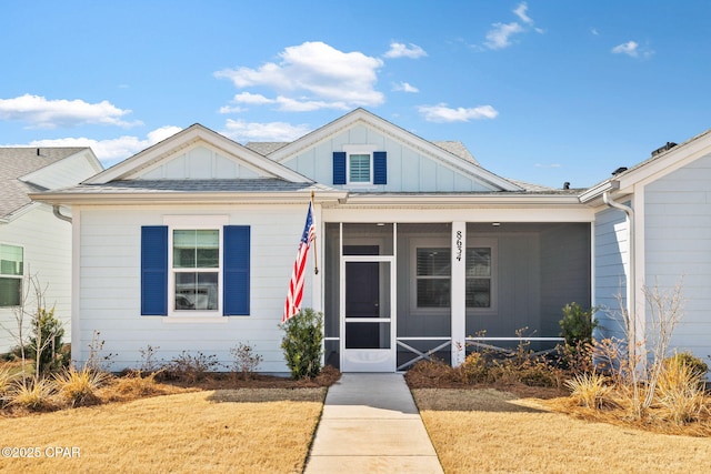 view of front of house featuring a sunroom, board and batten siding, and roof with shingles