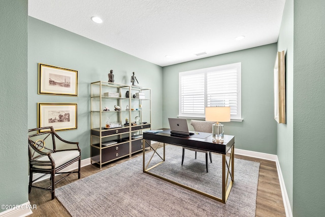 office with baseboards, a textured ceiling, and wood finished floors