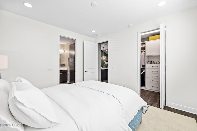 bedroom featuring a walk in closet, ensuite bathroom, recessed lighting, and wood finished floors