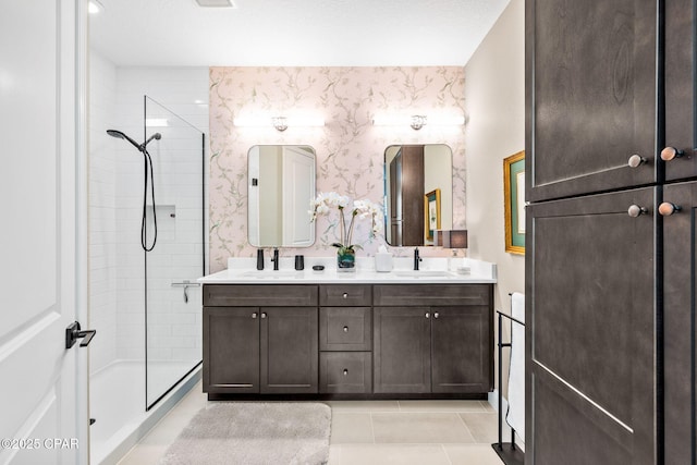 full bath with a sink, double vanity, wallpapered walls, and tiled shower