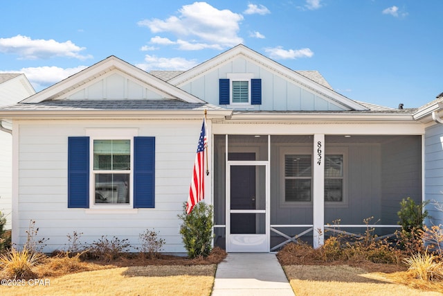 bungalow-style home with board and batten siding, a sunroom, and roof with shingles