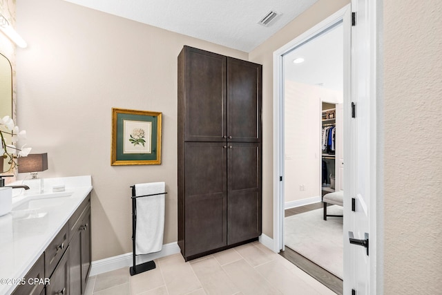 full bathroom with a sink, double vanity, tile patterned floors, a spacious closet, and visible vents