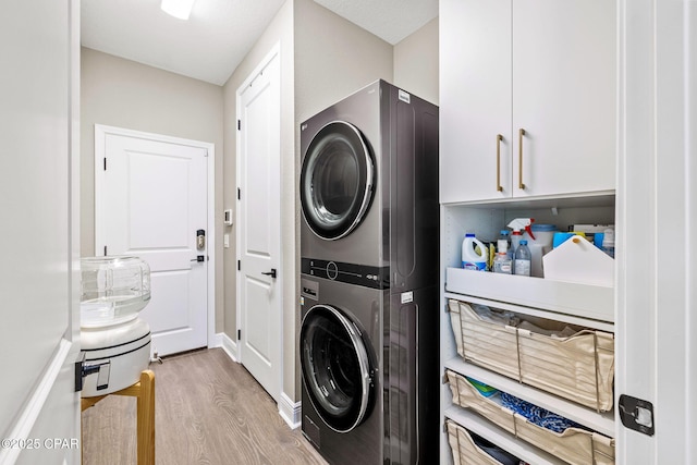 laundry room with cabinet space, stacked washing maching and dryer, and wood finished floors