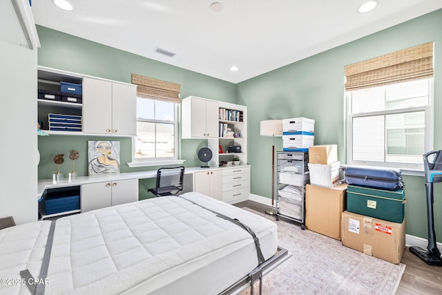 bedroom featuring visible vents, baseboards, recessed lighting, built in desk, and light wood finished floors