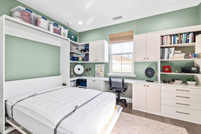 bedroom with built in study area, recessed lighting, dark wood finished floors, and visible vents